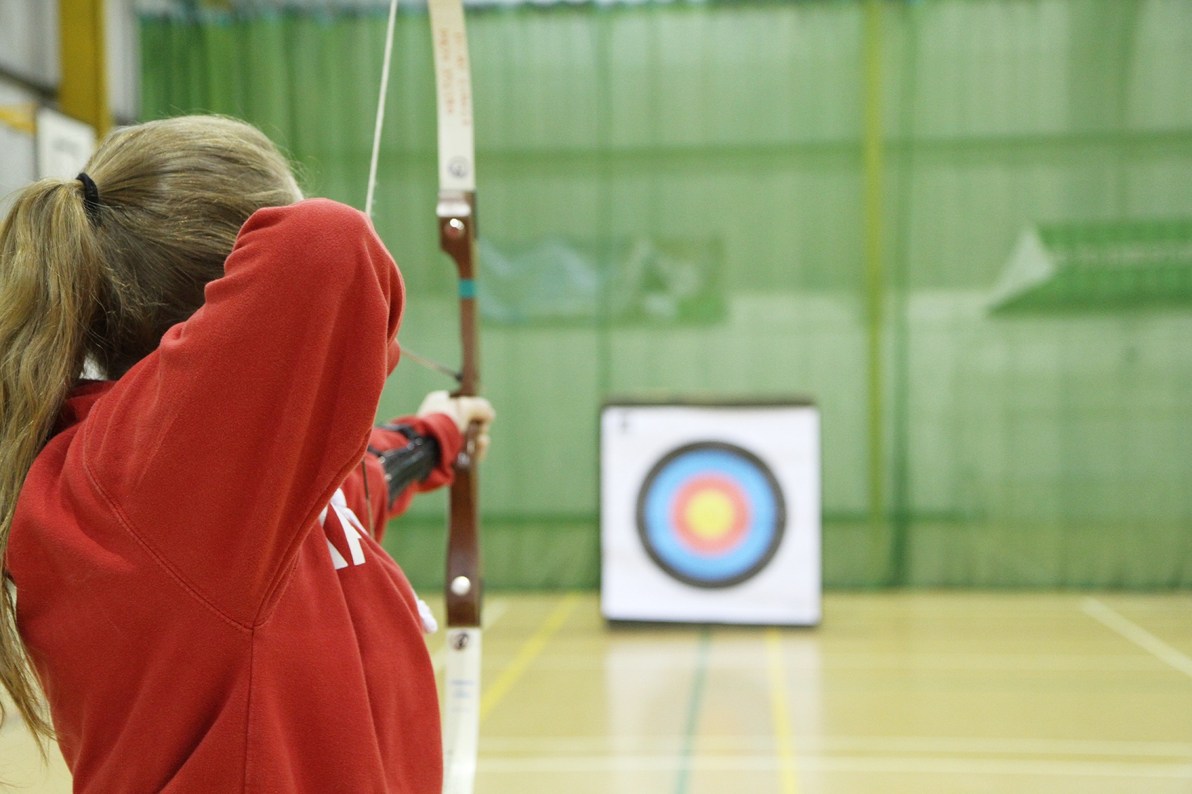 Girl doing archery in a sports hall