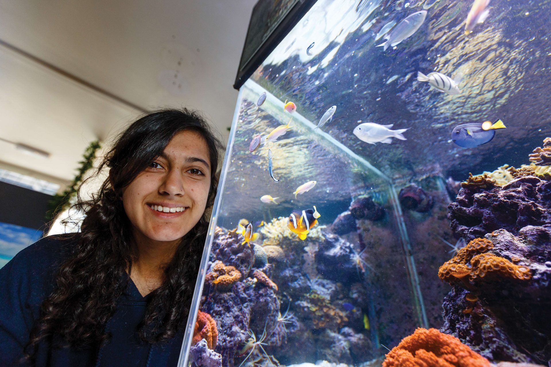 Falmouth Marine School marine biology student next to a tropical aquarium